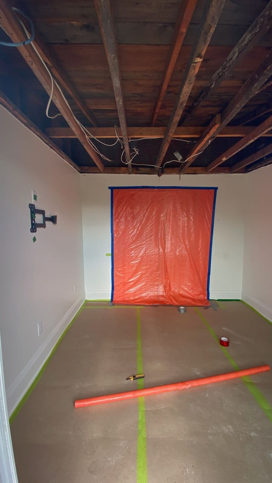 Room under containment during ceiling mold remediation — sealed poly over the doorway, floors fully protected, ceiling opened to the joists